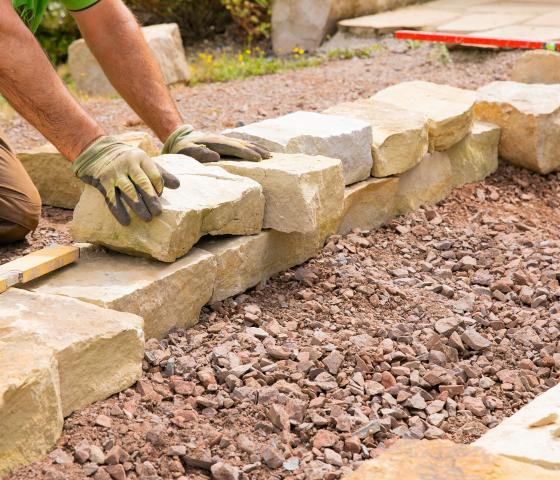 person building retaining wall from sandstone blocks